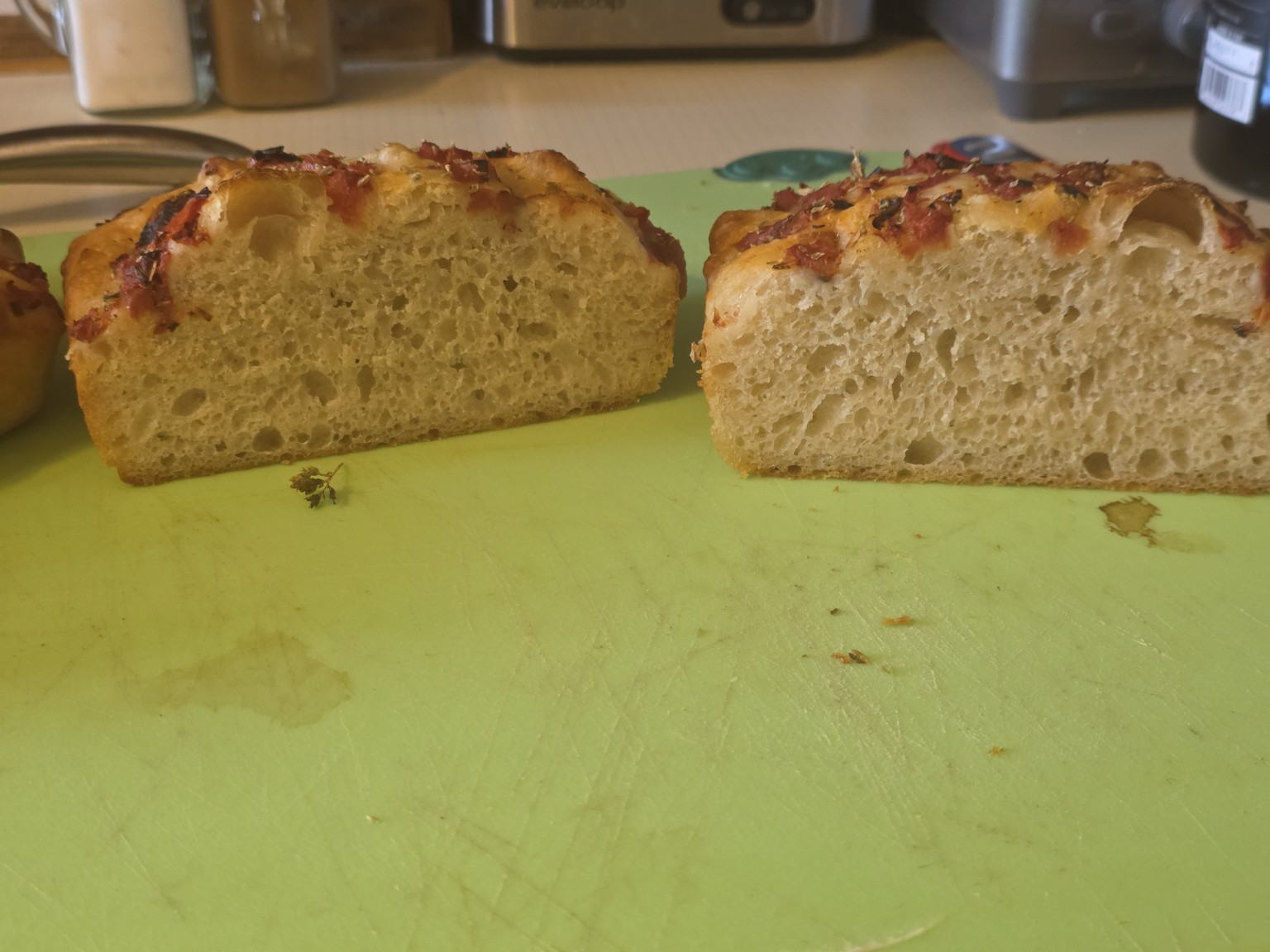 Two cut halves side by side. The crumb is aerated throughout, finer and tighter toward the base and more open near the top, with a few larger pockets under the crust. Both tops are domed.