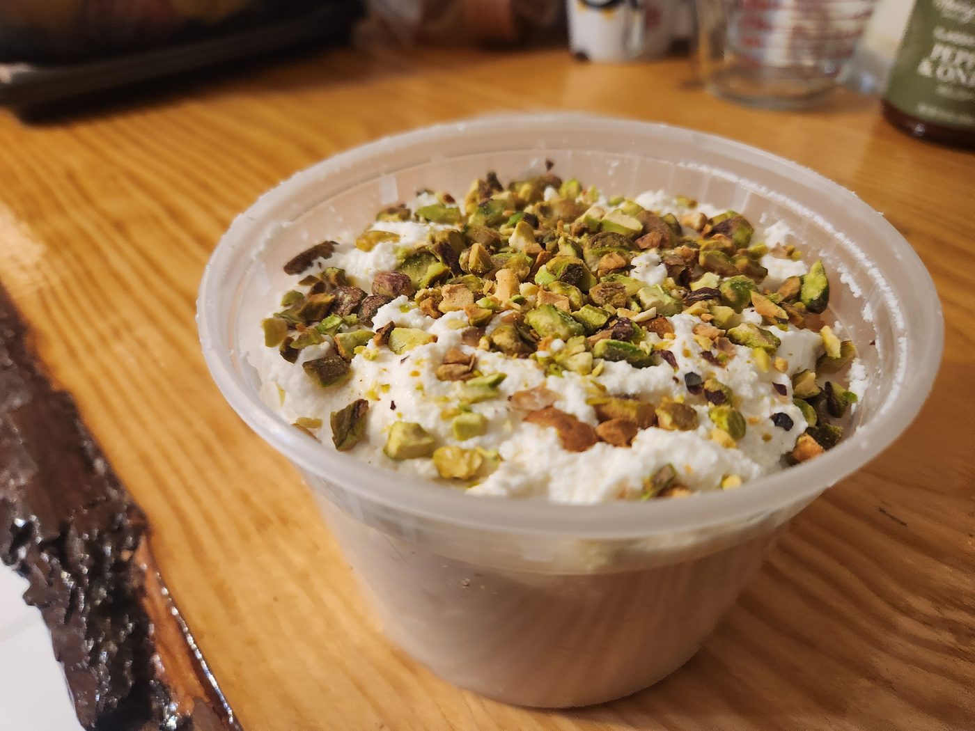 A deli tub of sweetened ricotta, still slightly curdy rather than beaten smooth, covered with roughly crushed green pistachios.