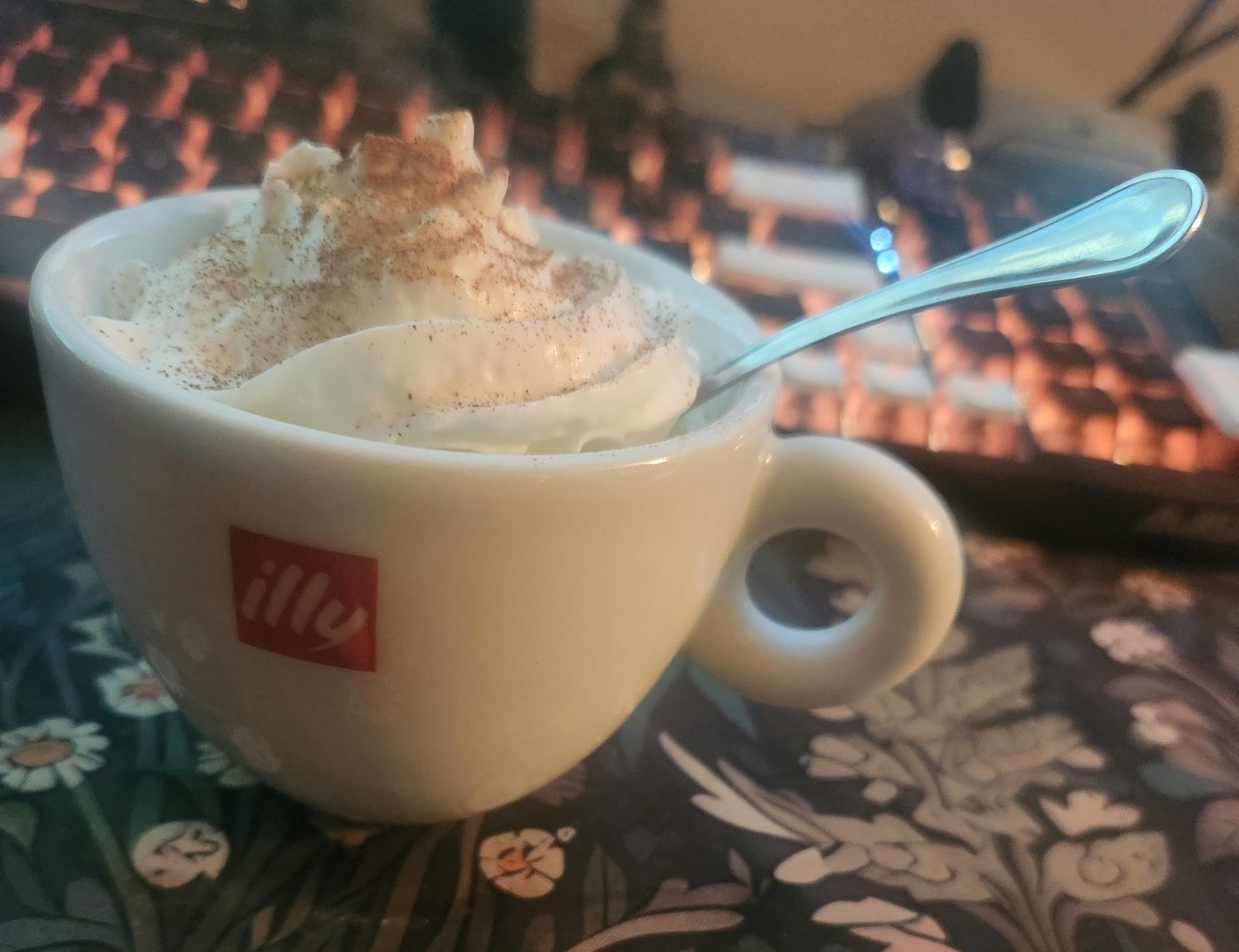 A cappuccino in a wide white cup with a thick dusted cap of foam.