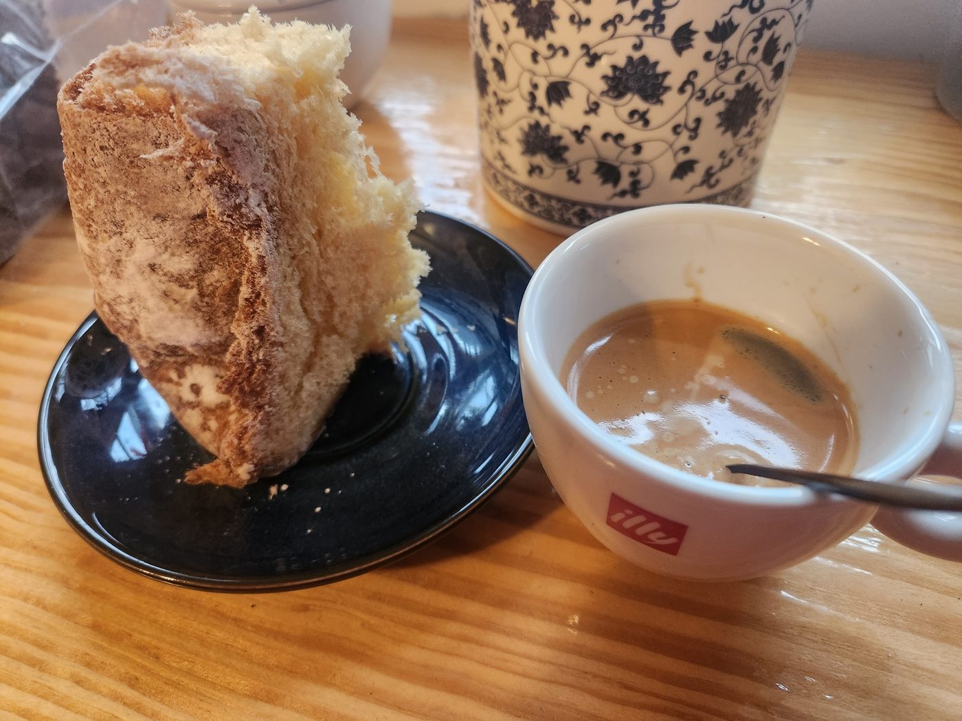 A thick slice of sourdough on a dark plate beside a small cup of espresso.