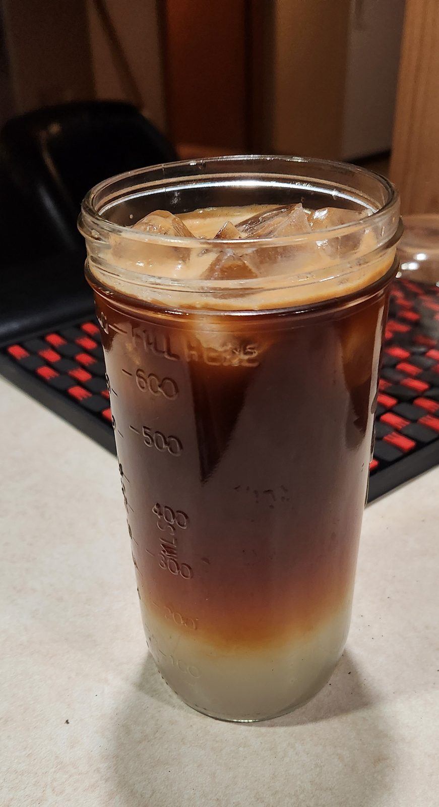 A tall glass of lemonade with a dark layer of espresso settling through it.