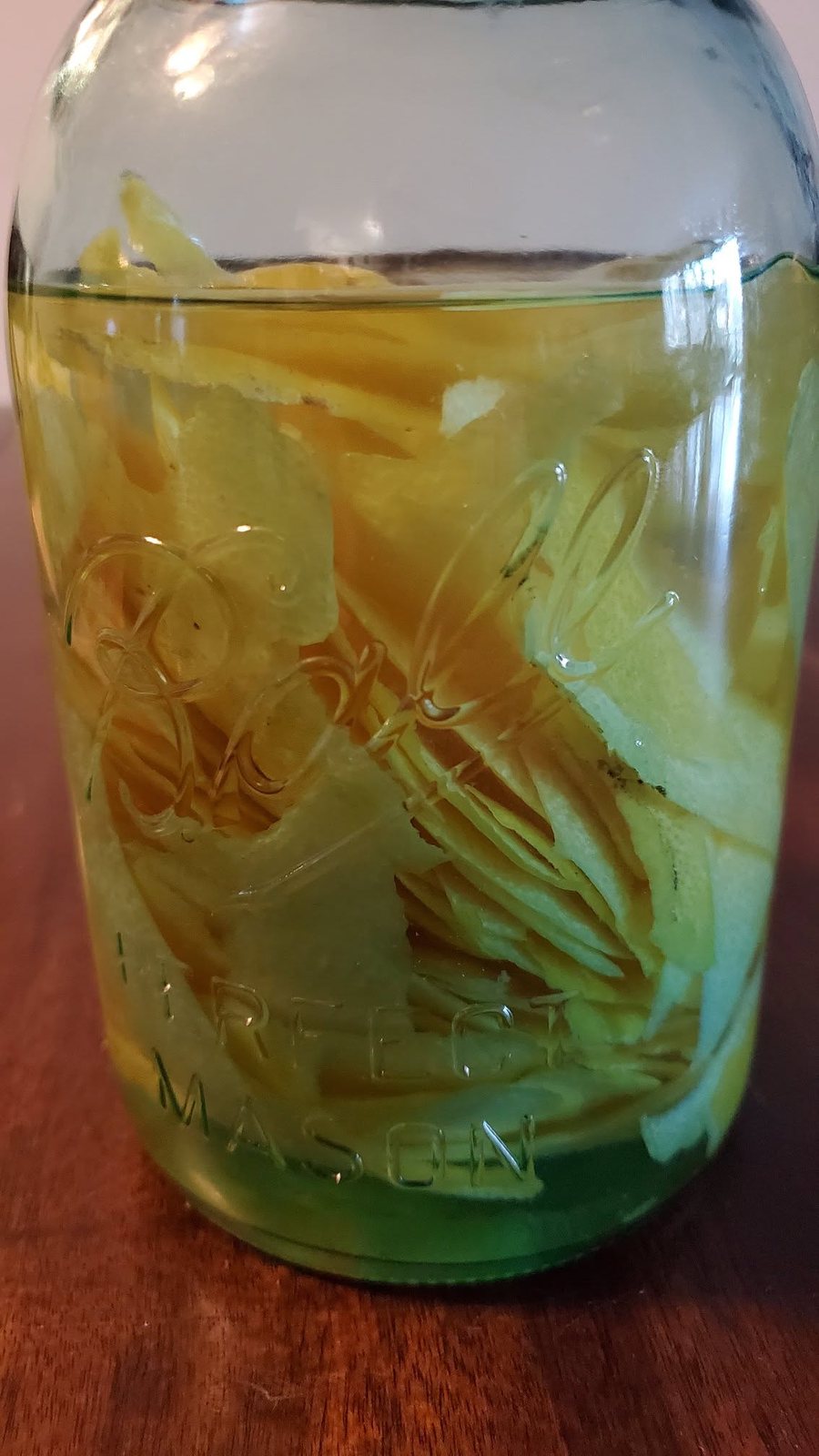 The same jar later in the maceration, the zest paled and the spirit deepened to a strong yellow.