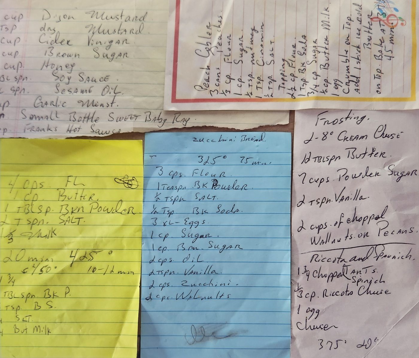 A spread of handwritten recipe cards and slips of paper on a table.