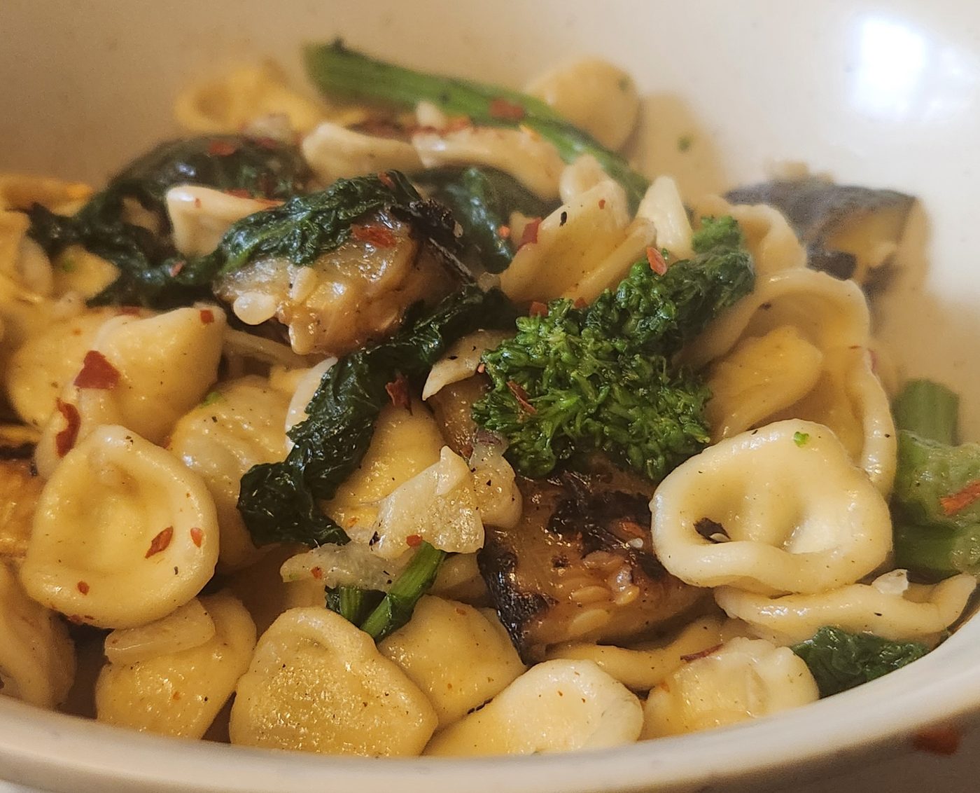 A bowl of orecchiette with dark green rapini and browned crumbled sausage.